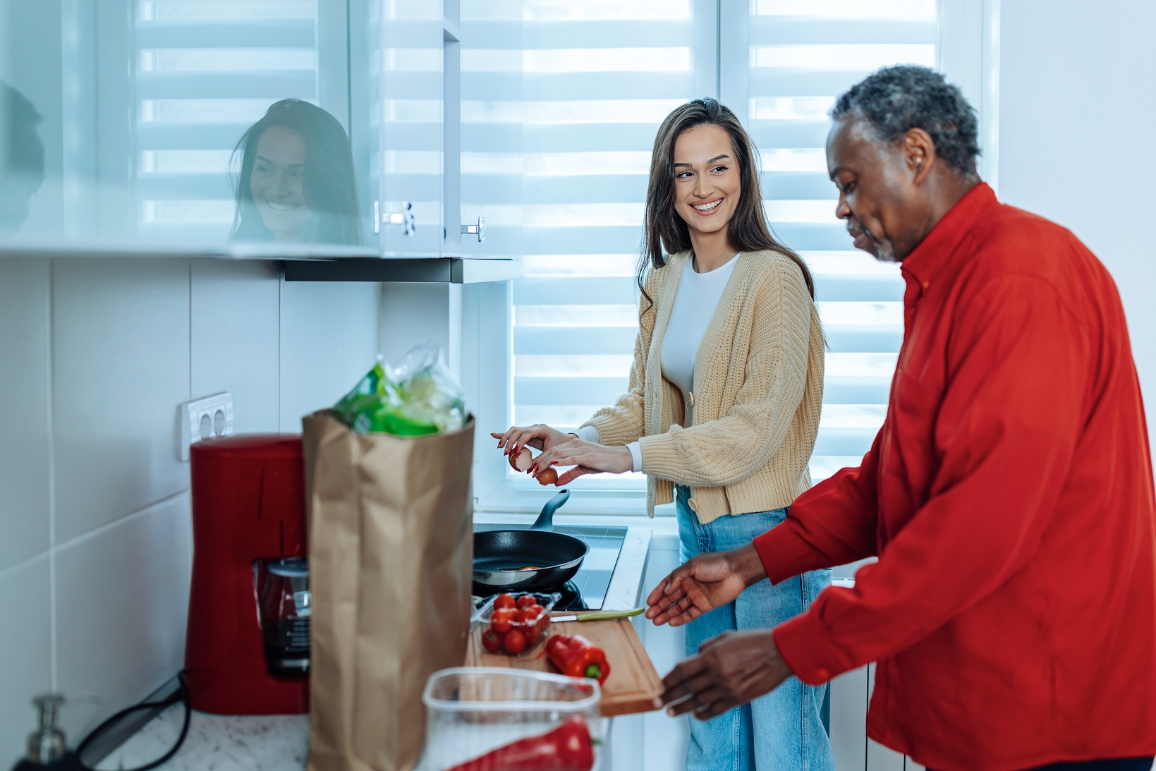 Kind young Caucasian female volunteer making dinner for a senior African American man